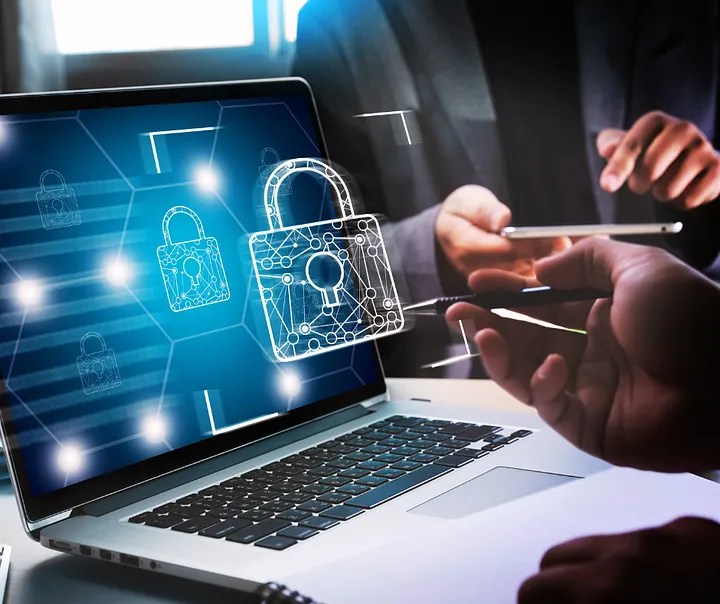 Laptop open with digital lock icon and users sitting around nearby